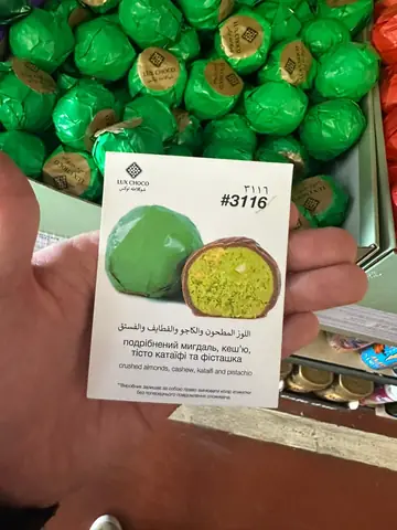 Chocolate-coated candy with crushed almonds, cashew, kataifi dough and pistachio filling, wrapper and cross-section