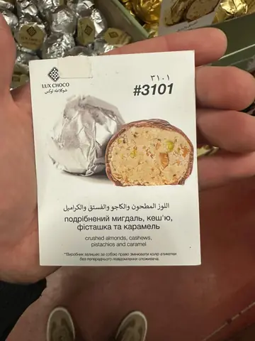 Chocolate-coated candy with crushed almonds, cashews, pistachios and caramel filling, wrapper and cross-section