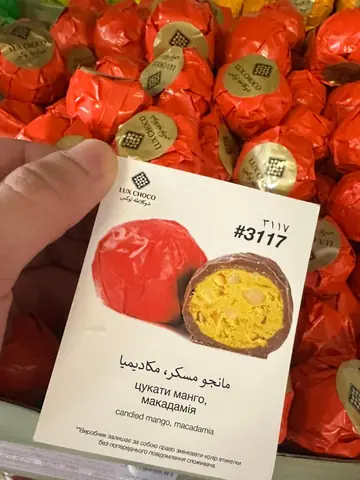 Chocolate-coated candy with candied mango and macadamia filling, wrapper and cross-section