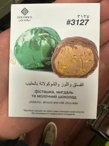Chocolate-coated candy with pistachio, almond and milk chocolate filling, wrapper and cross-section