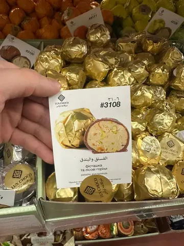 Chocolate-coated candy with pistachio and hazelnut filling, wrapper and cross-section