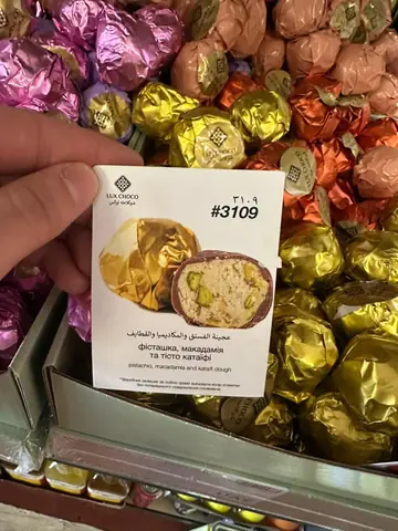 Chocolate-coated candy with pistachio, macadamia and kataifi dough filling, wrapper and cross-section